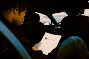 Driver reviewing an out-of-state traffic citation beside a phone, envelope, and driving record paperwork.